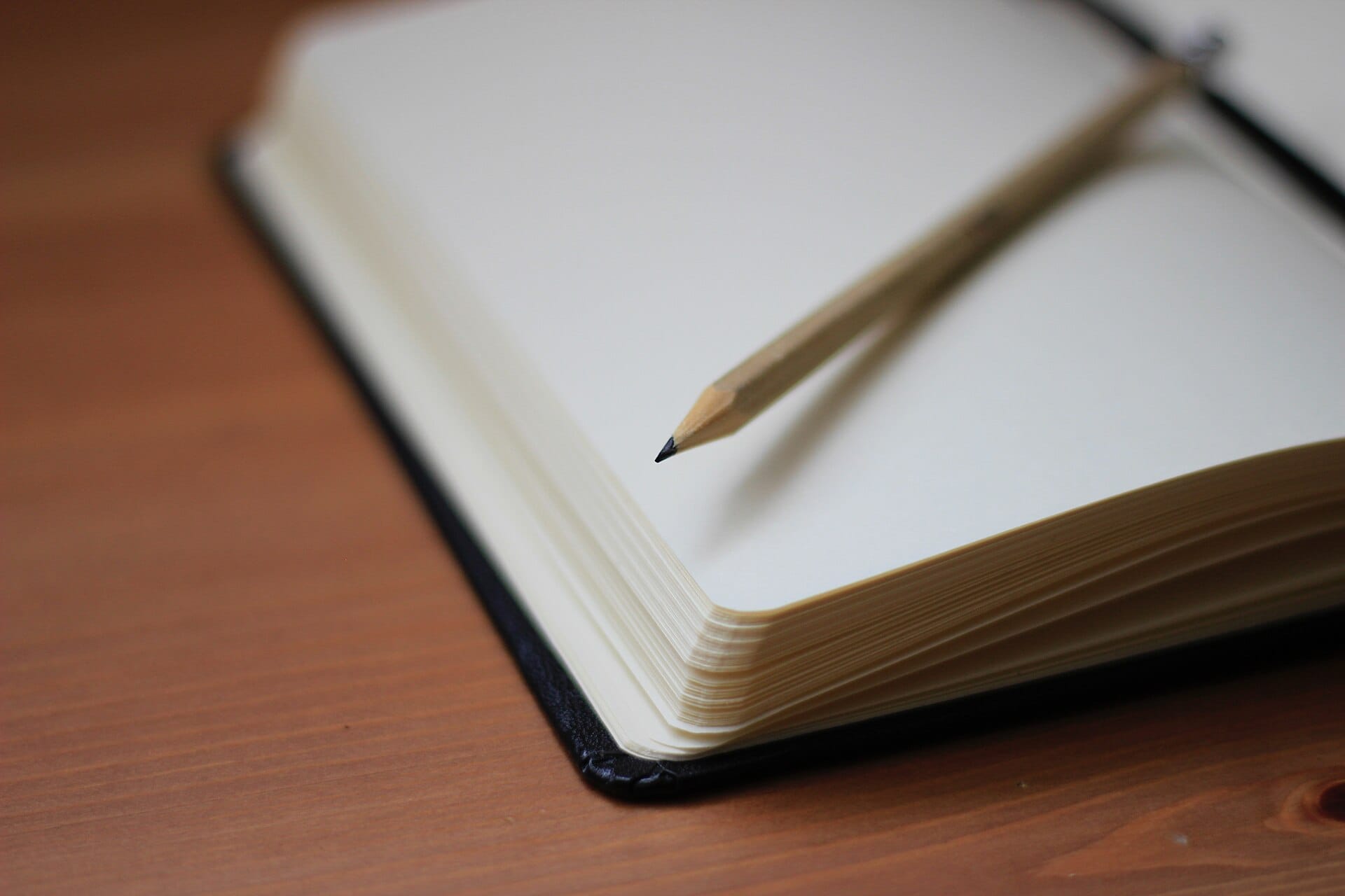 Open blank notebook and pencil on a wooden desk