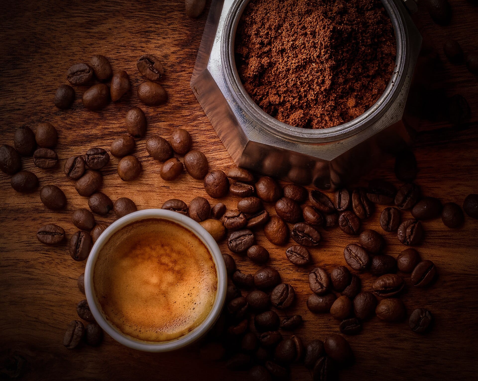 White ceramic coffee mug surrounded by roasted coffee beans